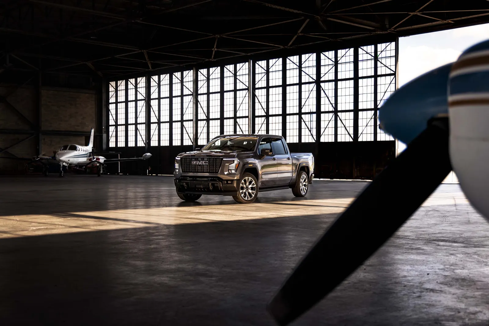 2027 GMC Sierra 1500 Denali in dark gray parked in an airplane hangar